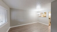 This single-floor residence offers a thoughtfully updated interior with a neutral color palette and consistent design choices throughout. The living and dining areas feature light-toned wood-look flooring, smooth gray walls, and a textured ceiling. A chandelier marks the dining space, which connects seamlessly to the kitchen via a pass-through counter. The kitchen is well-equipped with white shaker-style cabinetry, granite countertops, a classic subway tile backsplash, and stainless steel appliances including a refrigerator and dishwasher. A window above the sink allows natural light to brighten the workspace. The entry area continues the wood-look flooring and features a large window that fills the space with natural light. The bedrooms are finished with plush carpeting, ceiling fans with light fixtures, and multiple windows fitted with blinds for privacy and light control. Each bedroom includes a built-in closet with sliding doors and organized shelving. The bathroom features granite-topped vanity cabinetry, wood-look flooring, and a tub-shower combination adorned with large-format marble-style tile, complemented by a window for natural ventilation.