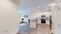 Located at 747 N DuPont Hwy in Dover, Delaware, this well-appointed one-bedroom, one-bathroom residence offers a thoughtfully designed single-floor layout. The open-concept living and dining area is bright and inviting, featuring warm neutral tones, light wood-style flooring, and large sliding glass doors that flood the space with natural light and lead to a private balcony with outdoor views.

The kitchen is a standout feature, showcasing white shaker-style cabinetry, dark countertops, a full suite of stainless steel appliances, and a peninsula with bar seating illuminated by pendant lighting — ideal for casual dining and entertaining.

The bedroom offers a comfortable, cozy retreat with a large window dressed with blinds and curtain panels, a closet, and continued use of warm flooring throughout. The bathroom is generously proportioned, featuring white cabinetry, a dark countertop with an undermount sink, a wide vanity mirror, and a shower-tub combination.

Throughout the residence, consistent warm beige walls and light flooring create a cohesive, clean aesthetic. The balcony provides an additional outdoor living space with views of the surrounding area, completing this well-rounded and functional home.