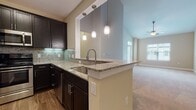 Located at 9601 Mercer Ct in Fredericksburg, Virginia, this single-floor residence offers a thoughtfully designed layout with modern finishes and practical amenities throughout. The kitchen serves as a central highlight, showcasing dark espresso cabinetry, granite countertops with a decorative tile backsplash, and stainless steel appliances including a range, microwave, and dishwasher. A peninsula with an undermount sink and pendant lighting above creates a natural connection to the adjacent living area, where plush carpeting and a ceiling fan contribute to a comfortable atmosphere. Multiple windows allow natural light to flow through the living space, offering outdoor views.

The bedrooms feature soft carpeting and are complemented by generous walk-in closets with built-in shelving. The bathrooms are finished with wood-look luxury vinyl plank flooring, with one bathroom offering a tub-shower combination fitted with brushed nickel fixtures. A dedicated laundry area includes washer and dryer hookups, overhead shelving, and tile flooring for added convenience. The overall design balances contemporary style with functional living, creating a cohesive and inviting home environment.