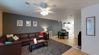 Torchlight Townhomes is a thoughtfully designed two-story townhome that balances comfort and functionality across its well-organized floor plan. The main level features an open-concept living and dining area highlighted by cool gray accent walls, ceiling fans with light fixtures, and light tile flooring. The living room offers generous seating space and large windows that invite natural light, while the adjoining dining area provides a welcoming spot for everyday meals. The kitchen is clean and efficient, featuring white cabinetry, ample counter space, a double-basin sink, a dishwasher, and additional white appliances, all set against bright tile flooring. Upstairs, the bedrooms are carpeted for comfort and each includes a ceiling fan, natural light from windows, and closet storage. The bedrooms are well-proportioned, offering space for both sleeping and a study area. The townhome includes two full bathrooms, each equipped with a tub-shower combination, a single vanity, and tile flooring. A dedicated in-unit laundry space houses a full-size Whirlpool washer and dryer, adding everyday convenience. Overall, the townhome presents a practical and comfortable living environment with a cohesive neutral palette throughout.