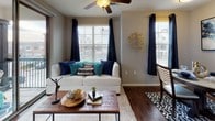The Maple is a thoughtfully designed 2-bedroom, 2-bathroom residence with a study, spread across three floors. The living room welcomes you with rich hardwood-style flooring, a ceiling fan, and multiple windows dressed in elegant drapes that invite an abundance of natural light. The kitchen is outfitted with dark espresso cabinetry, granite countertops, stainless steel appliances, and a double-basin sink, offering both style and functionality. Each bedroom features plush carpeting, generous windows, and easy access to the adjoining study — a versatile bonus space perfect for a home office or sitting area. The primary bedroom includes a spacious walk-in closet with wrap-around hanging rods and ample storage. Both bathrooms echo the home's refined aesthetic, featuring granite countertops, dark cabinetry, and wood-style flooring. The primary bath includes a glass-enclosed walk-in shower with tile surround and transom windows for added light. A dedicated laundry area accommodates a full-sized washer and dryer, adding everyday convenience. The multi-floor layout provides a sense of separation between living and sleeping spaces, contributing to an overall atmosphere that is both functional and comfortable.