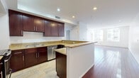 Located in the heart of Downtown Los Angeles, this two-bedroom, two-bathroom residence offers a well-designed single-floor layout that balances functionality with modern finishes. The open-concept kitchen and living area serves as the centerpiece of the home, featuring rich dark-wood cabinetry, granite countertops, stainless steel appliances including a dishwasher, microwave, and range, and a wraparound peninsula that provides both prep space and a casual dining option. Stone tile flooring anchors the kitchen, transitioning into warm hardwood floors that extend throughout the living area and bedrooms. The spacious living room is bathed in natural light from large windows that frame views of the surrounding Downtown cityscape. The generously sized primary bedroom features mirrored sliding closet doors and bright windows, while the second bedroom offers comparable natural light and hardwood flooring. Both bathrooms are finished with marble-style tile, with one featuring a full glass-enclosed shower. Recessed lighting throughout provides a clean, contemporary look. A hallway connects the private and shared spaces, contributing to an efficient and functional floor plan well-suited to urban living in one of Los Angeles's most vibrant neighborhoods.