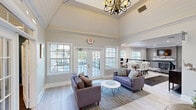 Located in Westlake, Ohio, this thoughtfully designed single-floor community space offers a seamless blend of comfort, functionality, and modern style. The welcoming entryway greets visitors with soaring vaulted ceilings clad in shiplap, an elegant chandelier, and a decorative round table — all bathed in natural light streaming through large windows and French doors that open to outdoor views. A bold teal accent wall adds a striking pop of color to the foyer.

The open-concept living room features two plush sofas, a tile-surround fireplace with a white mantel and wall-mounted TV, and light wood-look flooring that flows throughout the space. Adjacent to the living area, the combined dining room and kitchen offers a large dining table with white upholstered chairs, built-in workstations with monitors, and a kitchen bar with a white countertop and dark cabinetry — ideal for gatherings or remote work. A cozy café-style nook with bistro seating provides an additional spot for informal meetings.

The dedicated exercise room is generously sized and well-equipped, featuring treadmills, ellipticals, strength machines, free weights, wall mirrors, and mounted TVs — all set on durable flooring with ample natural light from surrounding windows.