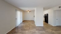 Located at 1501 E Grand Ave in Escondido, California, this single-floor residence offers a well-organized and practical layout with a clean, neutral aesthetic throughout. The open living and dining area is finished with warm wood-look flooring and features a ceiling fan, offering comfortable air circulation. Vertical blinds cover a sliding glass door that brings in generous natural light. Adjacent to the living space, the kitchen is efficiently designed with white cabinetry, gray countertops, a black appliance suite including a refrigerator and range, and a pass-through counter that connects to the main living area. The bedroom is carpeted and spacious, featuring a large sliding-door closet with built-in hanging rods for ample storage. A window allows natural light to brighten the room. The bathroom is well-appointed with white cabinetry, a gray countertop vanity, a single basin sink, and a wide mirror framed with overhead lighting. Textured ceilings are present throughout the unit, adding a classic touch to the interior. The space maintains a consistent neutral color palette of whites and beiges, creating a bright and adaptable environment suited to a variety of furnishing styles.