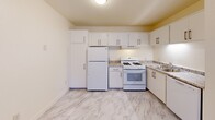 Located in Seaside, California, this one-bedroom, one-bathroom residence is thoughtfully arranged across three levels, making efficient use of its compact footprint. The main level serves as the heart of the home, housing the living room and a fully equipped kitchen. The kitchen features crisp white cabinetry with brushed hardware, granite-style countertops, a full suite of white appliances including a gas range, refrigerator, and dishwasher, and a marble-look luxury vinyl floor that adds a clean, modern aesthetic throughout. An accessible electrical panel is also found on this level. Staircases connect the three floors, with the mid-level providing transitional space between the main and upper floors. The upper level is home to the private bedroom, a cozy and quiet retreat finished with plush wall-to-wall carpeting and neutral warm-toned walls. Dedicated closet space supports practical storage needs. The bathroom offers a full tub and shower combination adorned with striking marble-style wall surrounds and open shelving, creating a clean and polished feel. Throughout the home, light-toned walls and consistent finishes contribute to a bright, cohesive atmosphere well-suited for comfortable everyday living.