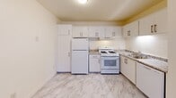 Located in Seaside, California, this one-bedroom, one-bathroom residence is thoughtfully arranged across three levels, making efficient use of its compact footprint. The main level serves as the heart of the home, housing the living room and a fully equipped kitchen. The kitchen features crisp white cabinetry with brushed hardware, granite-style countertops, a full suite of white appliances including a gas range, refrigerator, and dishwasher, and a marble-look luxury vinyl floor that adds a clean, modern aesthetic throughout. An accessible electrical panel is also found on this level. Staircases connect the three floors, with the mid-level providing transitional space between the main and upper floors. The upper level is home to the private bedroom, a cozy and quiet retreat finished with plush wall-to-wall carpeting and neutral warm-toned walls. Dedicated closet space supports practical storage needs. The bathroom offers a full tub and shower combination adorned with striking marble-style wall surrounds and open shelving, creating a clean and polished feel. Throughout the home, light-toned walls and consistent finishes contribute to a bright, cohesive atmosphere well-suited for comfortable everyday living.