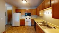 Located at 3301 W 51st St in Sioux Falls, South Dakota, this single-floor unit offers a practical and comfortable layout designed for everyday living. The living area is spacious and carpeted, featuring crown molding, a textured ceiling, and a sliding glass door fitted with vertical blinds that opens to an outdoor area, allowing natural light to fill the room. A pass-through window connects the living space to the kitchen, creating an open and airy feel between the two areas. The kitchen is well-appointed with warm wood cabinetry offering ample storage, light countertops, tile flooring, and a full suite of appliances including a refrigerator, electric range, built-in microwave, dishwasher, and a double-basin sink. The bedroom is generously sized with plush carpet, neutral walls, and flush-mount lighting, providing a clean and versatile space. The bathroom is neatly finished with a single-sink vanity, a large mirror, a tub-shower combination with chrome fixtures, and tile flooring that ties the space together cohesively. Throughout the unit, neutral tones and consistent finishes create a clean, move-in-ready atmosphere suited for a variety of lifestyles.