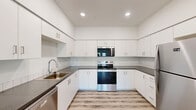 Located at 4001 E Jory St in Newberg, Oregon, this well-appointed 2-bedroom, 2-bathroom unit offers a clean, contemporary design across a single floor. Light-toned luxury vinyl plank flooring runs throughout the entire space, complementing the crisp white walls and creating a bright, cohesive aesthetic.

The open-concept living, dining, and kitchen area serves as the heart of the home. The kitchen is a standout feature, boasting a U-shaped layout with abundant white cabinetry extending to the ceiling, dark countertops, a white subway tile backsplash, and a full suite of stainless steel appliances including a refrigerator, electric range, over-the-range microwave, and dishwasher. Recessed lighting illuminates the space effectively.

The living area is bright and airy, benefiting from natural light through windows and a door that opens directly to a private balcony. Both bedrooms are comfortably sized — the primary bedroom offering generous proportions — with ample closet space and windows that bring in natural light. Three closets in total provide excellent storage throughout the unit.

The two bathrooms are finished consistently, each featuring a tub/shower combination, wood-look flooring, and clean white surrounds. A dedicated laundry area adds everyday convenience, rounding out this well-designed, move-in-ready home.