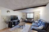 This single-floor, 2-bedroom, 1-bathroom home in Lowell, MA, offers a well-organized layout with a living room, kitchen, two bedrooms, a full bathroom, a hallway, and an impressive five closets throughout. The living room is a standout space, featuring a distinctive exposed dark wood ceiling beam and a textured ceiling that add architectural character. Natural light filters in through double-pane windows dressed with grommet curtains, creating a warm, inviting atmosphere. The kitchen is thoughtfully updated with crisp white shaker-style cabinetry, dark granite-look countertops, a mosaic tile backsplash, and hardwood flooring, providing both style and functionality. The primary bedroom is generously sized, offering carpet flooring, natural light from a large window, and a double sliding-door closet for ample storage. The second bedroom is also carpeted and well-lit, with its own window and closet access. The full bathroom includes a tiled tub-and-shower combination with classic white tile surround. A connecting hallway links all rooms efficiently, enhancing the overall flow of the home. With abundant closet space distributed throughout, this residence provides practical storage solutions to complement its comfortable, functional design.