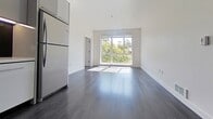 Located at 3015 San Pablo Ave, Unit 224 in Berkeley, CA, this modern condominium offers 860 square feet of thoughtfully designed single-floor living across 2 bedrooms and 2 bathrooms. Dark hardwood flooring flows consistently throughout the unit, creating a sleek, cohesive aesthetic against the crisp white walls.

The open living area is anchored by a large picture window that frames lush tree views and fills the space with abundant natural light. The kitchen features a galley-style layout with gray high-gloss cabinetry, stainless steel appliances including a full-size refrigerator, and under-cabinet lighting. The living and kitchen areas connect seamlessly, ideal for everyday functionality.

The primary bedroom measures 200 square feet and includes a sliding closet door and generous natural light. The second bedroom also benefits from a large window with urban views of the surrounding Berkeley streetscape. Both bathrooms are finished with dark mosaic tile flooring, white subway tile, and modern floating vanities. One bathroom includes a full soaking tub with an overhead shower. A dedicated in-unit laundry room houses a full-size side-by-side washer and dryer, adding exceptional convenience to this well-appointed urban residence.
