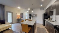 This well-appointed single-floor residence offers a thoughtfully designed open-concept layout that seamlessly connects the kitchen, dining, and living areas. The kitchen is a standout feature, showcasing dark espresso cabinetry, a white subway tile backsplash, stainless steel appliances, and a generously sized granite-topped island with bar seating for multiple guests — ideal for both everyday meals and entertaining. Recessed and pendant lighting illuminate the space, which is finished with light wood-look flooring throughout the main areas.

The living room is a comfortable and inviting retreat, featuring a ceiling fan, natural light from a large window with draping curtains, and ample room for a sectional sofa and accent furnishings. A dedicated workspace or dining nook adds functional versatility to the open floor plan.

The two bedrooms are carpeted for warmth and comfort. The primary bedroom includes a walk-in closet and a window that brings in natural light, while the secondary bedroom offers a cozy, well-organized layout. Both full bathrooms are finished with wood-look tile flooring, dark cabinetry with granite countertops, and a shower-tub combination, presenting a clean and cohesive aesthetic throughout the home.