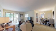 Located at 1 Makefield Rd in Morrisville, Pennsylvania, this single-floor residence offers a well-organized layout designed for comfortable everyday living. The living room is generously sized, featuring soft carpeting, a neutral color palette, and a sliding glass door that opens to a private balcony, allowing natural light to fill the space. A wall-mounted TV setup and cozy seating arrangement make it an inviting area for relaxation.

Adjacent to the living room, the dining area is defined by a pendant light fixture overhead and a round table with upholstered chairs, creating an intimate setting for meals. It connects seamlessly to the kitchen, which features rich dark wood cabinetry, stone-look countertops, wood-style flooring, and stainless steel appliances including a gas range, microwave, and dishwasher — along with a window that brings in natural light.

The unit includes two carpeted bedrooms, each offering ample closet space with sliding or hinged doors. The bedrooms are calm and well-proportioned, with soft lighting and neutral tones throughout. The full bathroom is clean and functional, featuring tile flooring, a tub-shower combination, and a wood-toned vanity. Overall, the residence presents a practical and pleasant living environment in a convenient Morrisville location.