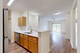 Located in Titusville, Florida, this well-appointed 2-bedroom, 2-bathroom residence offers a comfortable and functional single-floor layout. The open-concept design seamlessly connects the kitchen, dining, and living areas into one cohesive space. The kitchen features warm honey-toned cabinetry, white countertops, stainless steel appliances — including a range, microwave, and dishwasher — and a peninsula that provides additional counter space and a natural transition into the dining and living areas. Wood-style flooring runs throughout the main living areas and bedrooms, adding warmth and visual continuity. The spacious living room is brightened by a ceiling fan and a sliding glass door that opens to a private balcony with views of lush greenery. Both bedrooms are generously sized, featuring clean white walls and ample natural light. The primary bedroom includes access to a dedicated closet space equipped with wire shelving for organized storage. A dedicated laundry area and pantry add to the home's practicality. The two bathrooms are finished with tile flooring, wood-toned vanities, white countertops, and tub-shower combinations. With five closets spread throughout, this residence provides exceptional storage for everyday living.