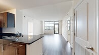 Located on an upper floor at 1028 S Walter Reed Dr in Arlington, Virginia, this well-designed unit offers a bright, open layout with contemporary finishes throughout. The open-concept living and dining area is anchored by rich hardwood-style flooring and floor-to-ceiling windows that frame expansive views of the surrounding Arlington skyline, with a glass door providing direct access to a private balcony. The kitchen features rich dark cabinetry, stainless steel appliances including a refrigerator, microwave, and range, dark granite countertops, and a peninsula with bar seating that seamlessly connects to the living space. Light tile flooring in the entry and kitchen transitions gracefully to hardwood-style flooring in the main living areas. The bedrooms are carpeted for comfort, with the primary bedroom benefiting from its own balcony access through glass doors, offering additional outdoor views. Both bathrooms are finished with light tile flooring, white subway-tiled tub-shower combinations, modern gray vanity cabinetry, and clean white countertops. A dedicated bathroom corridor provides added privacy and functionality. Throughout the unit, neutral tones, textured ceilings, and abundant natural light create a clean, modern ambiance well-suited to urban living in the Arlington area.