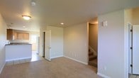 This three-floor residence is designed with functionality and comfort in mind, offering a thoughtfully arranged layout that makes excellent use of its vertical space. The main living area features warm, neutral-toned carpet underfoot and smooth, light-colored walls that create a bright and welcoming atmosphere. Recessed lighting in the ceiling provides clean, even illumination throughout the space. A staircase leads between the floors, connecting each level with ease and adding a sense of depth to the overall layout. Adjacent to the main living area, a doorway opens into a kitchen space where tile flooring and white appliances, including a refrigerator, contribute to a practical and functional cooking environment. The transitions between rooms are clean and open, promoting a natural flow from one area to the next. White panel doors and crisp baseboards throughout add a tidy, well-maintained character to the interior. The neutral color palette and understated finishes create a versatile backdrop, lending itself well to a variety of furnishing styles. Spanning three full floors, this residence provides ample room for living, working, and relaxing, making it a spacious and adaptable home.