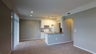 Located at 1669 College Park Dr in Columbus, Ohio, this single-floor residence offers a clean, functional layout designed for comfortable everyday living. The open-concept main living area features neutral gray walls, plush carpeting, and recessed lighting that create a bright and inviting atmosphere throughout.

The kitchen is a standout feature, outfitted with crisp white cabinetry, a white electric range, and a peninsula-style breakfast bar with a built-in sink and dark countertops. Track lighting above the kitchen adds focused illumination, enhancing both form and function. The peninsula provides a natural transition between the kitchen and the living area, making the space well-suited for both cooking and entertaining.

The open living space is generously sized, offering ample room for a variety of furniture arrangements. Neutral tones throughout the walls and flooring provide a versatile backdrop adaptable to many décor styles. A hallway visible from the main living area suggests additional private rooms, contributing to the overall practical flow of the floor plan. The combination of modern lighting, well-organized cabinetry, and open sightlines makes this a highly livable and well-appointed single-story residence.