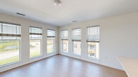 This well-designed single-floor unit offers a clean, contemporary aesthetic defined by bright white walls, light hardwood-style flooring in the main living areas, and an abundance of natural light throughout. The expansive living area is a standout feature, boasting a wraparound arrangement of tall windows fitted with adjustable blinds that frame views of the surrounding neighborhood and green spaces, flooding the room with daylight. A glass-panel door leads directly to a private balcony, further extending the connection to the outdoors. The kitchen is thoughtfully appointed with white shaker-style cabinetry, light quartz countertops, a classic subway tile backsplash, and a full suite of stainless steel appliances including a refrigerator, range, and microwave. A peninsula with a built-in sink and pendant lighting adds both function and style. The bedrooms feature neutral carpet, generous closet space including sliding-door and walk-in options, and windows offering neighborhood views. The bathroom is finished with a white vanity, quartz countertop, a tub-shower combination, and light wood-tone flooring, maintaining the unit's cohesive, modern palette. Overall, the space presents a bright, functional, and well-appointed living environment.