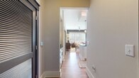 This 1050 square foot apartment offers a perfect blend of style and functionality. The space boasts two bedrooms and two bathrooms, ideal for small families or those seeking a roommate setup. The heart of the home is an open-concept living area, showcasing a striking design with contrasting wall colors - a deep charcoal and a soothing teal - creating a sophisticated ambiance.

Large windows flood the space with natural light, enhanced by white trim and blinds. The living room features a brown leather sofa adorned with decorative pillows, complemented by a unique striped coffee table and a textured accent chair. A round mirror and carefully curated decor pieces add visual interest.

The 170 square foot primary bedroom promises ample space for rest and relaxation. Throughout the apartment, you'll find two bathrooms, two closets, and two hallways, ensuring convenience and storage. The kitchen, while not visible in the image, is integrated into the open living space, promoting a social atmosphere.

Hardwood floors run throughout, adding warmth and elegance to the contemporary design. A cowhide rug beneath the coffee table introduces an element of texture. The overall aesthetic is modern and urbane, perfect for those who appreciate a stylish yet comfortable living environment.
