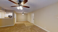 Located at 179 N Royal Oaks Blvd in Franklin, Tennessee, this single-story home offers a well-organized, functional layout throughout. The living area is generously proportioned, featuring warm neutral-toned carpet, a ceiling fan with light fixture, and a tiled entryway. A fireplace serves as a focal point in the main living space, which also includes French doors that invite natural light and provide outdoor access. A pass-through window connects the living area to the kitchen, enhancing the open feel between spaces. The galley-style kitchen is equipped with white cabinetry, a black appliance suite including a gas range, refrigerator, and built-in microwave, complemented by light tile flooring and stone-look countertops. Multiple bedrooms are carpeted and feature ceiling fans, ample closet space with double-door closets, and windows fitted with blinds for natural light and privacy. The bathrooms are clean and functional — one features a white vanity with a stone countertop, a large mirror, and updated oil-rubbed bronze fixtures, while a second includes a tub/shower combo and tile flooring. Textured walls and ceilings are consistent throughout, contributing to the home's cohesive, neutral aesthetic.