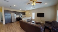 This three-story home is designed to maximize functionality across multiple levels, connected by a staircase with a classic white balustrade and a wall-mounted handrail. The main living area features an open-concept layout where the kitchen flows seamlessly into the living and dining spaces. Hardwood-style flooring runs throughout the main level, complemented by recessed lighting and ceiling fans for comfort. The kitchen is appointed with dark espresso cabinetry, granite countertops, stainless steel appliances including a refrigerator, range, and microwave, and a peninsula with bar seating and pendant lighting overhead.

The living areas are bright and welcoming, with natural light filtering through slatted blinds on multiple windows. Each bedroom is carpeted and includes a ceiling fan and ample closet space, offering a comfortable and functional retreat. The bathrooms are consistently finished with dark vanity cabinetry, granite-style countertops, and clean white tile surrounding the tub-shower combinations or walk-in showers. Cool blue-gray wall tones in the bathrooms provide a calm contrast to the warm neutral palette found throughout the rest of the home.
