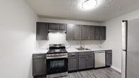 Located at 1699 Shanley Dr in Columbus, Ohio, this single-floor residence offers a well-organized layout designed for comfortable everyday living. The kitchen serves as a standout feature, showcasing dark gray shaker-style cabinetry, marble-look countertops, and a full suite of stainless steel appliances including a gas range, dishwasher, and refrigerator. Light wood-tone vinyl plank flooring grounds the kitchen with a clean, modern aesthetic. The living area transitions between hard flooring and plush wall-to-wall carpeting, providing a warm and inviting atmosphere. Multiple bedrooms are finished with neutral-toned carpet and feature windows that allow natural light to filter in, offering views of the surrounding outdoor environment. At least one bedroom includes a built-in closet with shelving for added storage convenience. The full bathroom is bright and functional, featuring a tub-shower combination, a white vanity, and wood-look vinyl flooring that complements the overall design palette. Throughout the residence, textured ceilings and neutral wall tones create a consistent, understated backdrop that accommodates a variety of interior styles. The floor plan, as seen in the dollhouse overview, offers a practical and efficient use of space across all rooms.