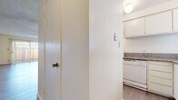 This single-floor, 2-bedroom, 2-bathroom residence is thoughtfully laid out to maximize functionality and comfort. The living room is a bright, open space featuring light wood-style flooring, a textured ceiling, and a large sliding glass door with vertical blinds that flood the room with natural light and provide outdoor access. Adjacent to the living room, the galley-style kitchen is efficiently designed with white cabinetry, granite-style countertops, a white electric range, and a window above the sink that brings in additional natural light. Light wood-look flooring continues throughout the kitchen and hallways. The two bedrooms are well-proportioned, each featuring wood-style flooring, windows with blinds for natural light and privacy, and textured ceilings. The second bedroom includes a sliding closet with built-in shelving for ample storage. Both bathrooms are finished with granite-topped white vanities and light wood-style flooring; one features a tub/shower combination, while the other is configured as a half bath with a toilet and vanity. Two hallways connect the rooms, providing a smooth and logical flow throughout the residence. The overall aesthetic is clean, neutral, and move-in ready.