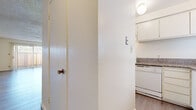 This single-floor, 2-bedroom, 2-bathroom residence is thoughtfully laid out to maximize functionality and comfort. The living room is a bright, open space featuring light wood-style flooring, a textured ceiling, and a large sliding glass door with vertical blinds that flood the room with natural light and provide outdoor access. Adjacent to the living room, the galley-style kitchen is efficiently designed with white cabinetry, granite-style countertops, a white electric range, and a window above the sink that brings in additional natural light. Light wood-look flooring continues throughout the kitchen and hallways. The two bedrooms are well-proportioned, each featuring wood-style flooring, windows with blinds for natural light and privacy, and textured ceilings. The second bedroom includes a sliding closet with built-in shelving for ample storage. Both bathrooms are finished with granite-topped white vanities and light wood-style flooring; one features a tub/shower combination, while the other is configured as a half bath with a toilet and vanity. Two hallways connect the rooms, providing a smooth and logical flow throughout the residence. The overall aesthetic is clean, neutral, and move-in ready.