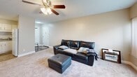 Located at 2075 Regency Rd in Lexington, Kentucky, this single-floor residence offers a practical and comfortable layout with two bedrooms and two bathrooms. The living room serves as the heart of the home, featuring plush carpeting, a ceiling fan with light fixture, and a large window with vertical blinds that fills the space with natural light and offers pleasant outdoor views of surrounding greenery. The kitchen is well-appointed with white cabinetry, ample counter space, and a full suite of white appliances including a range, dishwasher, refrigerator, and built-in microwave, all set atop durable tile flooring. The primary bedroom offers two closets and a window with vertical blinds, providing comfortable storage and natural light. The second bedroom is carpeted and also features a window. Both bathrooms are finished with stone-look tile flooring; one includes a walk-in shower with glass doors and conveniently houses an in-unit washer, while the second features a rich wood-toned vanity with a lighted mirror. A connecting hallway and utility room round out the efficient floor plan, making this a well-organized and functional living space.