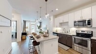 Located at 4454 Tropea Way in Jacksonville, Florida, this single-floor residence presents a thoughtfully designed open-concept layout that seamlessly connects the kitchen, dining, and living areas. The kitchen serves as a central highlight, featuring a generously sized island with granite countertops and seating, complemented by pendant globe lighting overhead. Cabinetry combines crisp white upper cabinets with rich dark lower cabinets, framing a subway tile backsplash. Stainless steel appliances — including a French door refrigerator, electric range with microwave, and dishwasher — complete the well-equipped space. Wood-look flooring flows throughout the main living areas, adding warmth and continuity.

The living room is bright and welcoming, benefiting from large windows and a glass-paned door that opens to a balcony, allowing abundant natural light and outdoor views. The bedrooms feature plush carpeting, large windows, and ample space. The bathroom is finished with granite countertops, dark wood cabinetry, a large mirror, and a walk-in closet with built-in shelving. An in-unit laundry area is also present. Overall, the space offers a clean, contemporary aesthetic with quality finishes throughout.