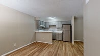 This single-story unit offers a practical and well-appointed layout designed for comfortable everyday living. The open-concept kitchen and living area serve as the heart of the space, featuring warm wood-look laminate flooring that flows seamlessly throughout. The kitchen is equipped with grey cabinetry, a neutral tile mosaic backsplash, white quartz-style countertops, and a peninsula that provides additional prep space and separates the kitchen from the living area. Stainless steel appliances, including a refrigerator and dishwasher, complement the modern aesthetic, while a white electric range adds a classic touch. A textured popcorn ceiling is consistent throughout the unit. The bedroom is bright and airy, benefiting from a window with exterior views and a ceiling fan that enhances air circulation. A sliding-door closet with built-in wire shelving provides organized storage. The bathroom features a white vanity with ample counter space, a full tub-shower combination with white tile surround, and wood-look flooring that ties the space together. Neutral-toned walls throughout the unit create a clean, versatile backdrop suitable for a variety of décor styles.
