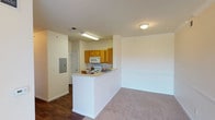 This single-story space offers a practical and functional layout with a clean, neutral aesthetic throughout. The open-concept living and kitchen area is connected by a white peninsula counter that provides both a workspace and a natural divider between the two zones. The kitchen is equipped with warm oak cabinetry offering ample upper and lower storage, light-toned countertops, a white electric range, over-the-range microwave, and a stainless steel double sink. An electrical panel is conveniently accessible within the kitchen area. The living space features neutral carpet and crown molding detail along the upper wall, contributing a subtle touch of refinement.

The bedrooms are carpeted and feature ceiling fans with light fixtures, and each room benefits from natural light provided by windows fitted with blinds. The rooms offer a clean, versatile canvas suitable for various furniture arrangements.

Two full bathrooms serve the unit, each featuring wood-style flooring, a tub-shower combination with white tile surround, and a toilet. One bathroom also includes a vanity with light countertop surface. The overall color palette throughout the space is consistently light and neutral, creating a cohesive and understated atmosphere.