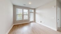 Located at 5306 Acadia Heights Dr in Charlotte, NC, this thoughtfully designed one-bedroom, one-bathroom residence offers a clean, modern aesthetic across a single level. Light hardwood-style flooring flows consistently throughout the space, complementing the neutral gray-toned walls and crisp white trim found in every room.

The open-concept kitchen and living area serves as the heart of the home. The kitchen is well-appointed with gray shaker-style cabinetry, granite countertops, a white subway tile backsplash, and a full suite of stainless steel appliances including a refrigerator with ice maker, range, microwave, and dishwasher. A central island with a granite surface and pendant lighting overhead adds both functionality and style.

The living area is bright and welcoming, with multiple windows fitted with blinds allowing ample natural light. A private entrance door with a transom window further enhances the light and accessibility of the main living space.

The bedroom is a comfortable, well-lit retreat featuring two windows with outdoor views and a ceiling fan. An adjacent closet with built-in shelving provides convenient storage solutions.

The bathroom is finished with a dual-sink vanity featuring blue-gray cabinetry and granite countertops, a large mirror, and hardwood-style flooring that continues the cohesive design language of the home. A hallway connects all rooms efficiently, completing this well-organized and modern residence.