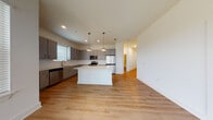 Located at 1251 Ray Charles Blvd in Tampa, Florida, this single-floor residence offers a thoughtfully designed open-concept layout with contemporary finishes throughout. The kitchen serves as the centerpiece of the living area, showcasing gray cabinetry with brushed nickel hardware, white quartz countertops, a classic subway tile backsplash, and a full suite of stainless steel appliances including a refrigerator, range, microwave, and dishwasher. A central island with a white countertop provides additional workspace, while stylish pendant lights overhead add a modern touch. Light-toned hardwood flooring flows seamlessly through the main living areas, enhancing the bright and airy atmosphere. The bedrooms offer plush carpeting and generous natural light through large windows fitted with blinds. The primary bathroom features a dual-sink vanity with gray cabinetry, white quartz countertops, a large framed mirror, and a glass-enclosed shower. A second bathroom includes a tiled shower-tub combination, complementing the space's clean aesthetic. Ceiling fans in the living areas contribute to everyday comfort. The overall design is clean, modern, and functional, making this residence a well-appointed home in the heart of Tampa.