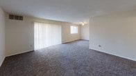 This single-floor residence offers a thoughtfully arranged layout, as seen in the floor plan, encompassing a generous living area, kitchen, multiple bedrooms, and two bathrooms. The expansive living room is finished with plush dark carpet and features large vertical blinds covering a sliding glass door that allows abundant natural light to fill the space. A ceiling fan adds functionality, while a secondary window further brightens the room.

The kitchen is equipped with warm-toned wood cabinetry, dark granite-style countertops, a stainless steel sink, a gas range, and a dishwasher, all complemented by wood-look flooring that adds a practical contrast to the carpeted areas.

The bedrooms are carpeted and feature neutral walls, natural light from windows with blinds, and ample closet space. One bedroom includes a walk-in closet and direct access to a bathroom.

The two bathrooms offer distinct configurations: one includes a glass-enclosed neo-angle shower with tile surround and decorative mosaic accents, while the second features a full tub-shower combo with tiled walls, a dark wood vanity, granite countertop, and wood-look flooring. Both bathrooms are clean and well-finished, contributing to the overall functional and understated character of the space.