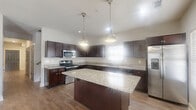 Located in Kennesaw, GA, this two-story home offers a thoughtfully designed layout across two floors. The main level provides an open-concept kitchen and living area with warm hardwood-style flooring, ceiling fans, and natural light from multiple windows. The kitchen is a standout feature, showcasing rich dark cabinetry, granite countertops, stainless steel appliances including a range, microwave, dishwasher, and refrigerator, plus a central island with pendant lighting — ideal for both cooking and entertaining. A pantry and convenient half bathroom are also found on this floor. The living area features a welcoming front entry door with glass pane accents and an adjacent window that fills the space with natural light. Upstairs, four bedrooms offer plush carpeting and ceiling fans, including a primary suite with an en-suite bathroom and walk-in closet. The remaining bedrooms are well-sized and share access to additional full bathrooms, each featuring tub-shower combinations and clean, neutral finishes. Six closets throughout the home provide ample storage. A dedicated laundry room and multiple hallways add to the home's practical functionality. The neutral color palette and consistent finishes create a cohesive and move-in-ready feel throughout.