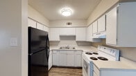 This single-story residence at The Northern in Little Rock, Arkansas offers a practical and comfortable layout across two bedrooms and one and a half bathrooms. The living area features dark wood-style vinyl plank flooring that extends throughout the main spaces, complemented by crown molding and neutral gray walls that create a clean, cohesive aesthetic. A ceiling-mounted light fixture provides consistent illumination throughout the common areas.

The U-shaped kitchen is well-equipped with ample white cabinetry for storage, white laminate countertops, a double-basin sink, a white electric coil-burner range, an over-the-range ventilation hood, and a black refrigerator. Wood-style flooring continues into this space, making it easy to maintain.

Both bedrooms are carpeted and feature ceiling fans with integrated lighting, as well as windows with blinds that allow natural light to filter in. The rooms offer versatile, open layouts suitable for various furniture arrangements.

The full bathroom includes a white tub and shower surround combo with built-in shelving niches, wood-style flooring, and a vanity. The overall ambiance of the unit is straightforward and functional, with a neutral palette throughout that provides a move-in-ready foundation.