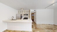 Located at 3602 Garrott St. in Houston's vibrant Montrose neighborhood, this single-story, one-bedroom, two-bathroom unit offers a thoughtfully designed layout that maximizes every square foot. Natural stone tile flooring flows continuously throughout the entire space, lending a cohesive and polished look to every room.

The kitchen is a standout feature, equipped with stainless steel appliances including a refrigerator, range, and microwave, all complemented by white cabinetry with glass-panel upper doors and light quartz countertops. A peninsula with an integrated sink opens toward the living area, creating an efficient and functional workspace.

The bedroom is a comfortable retreat, featuring a ceiling fan with light fixture and a window that allows natural light to fill the room. Two closets provide generous storage options for the space. The clean white walls throughout maintain a bright, airy atmosphere.

Two full bathrooms serve the unit, one of which features classic white subway tile surrounding a shower-tub combination, a quartz-topped vanity, and matching stone tile flooring. The consistent use of neutral tones and quality finishes across the unit creates a clean, modern aesthetic suited for everyday living.