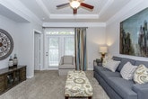 This single-floor residence offers a thoughtfully designed layout that balances comfort and functionality throughout its living spaces. The living room serves as the heart of the home, showcasing an elegant tray ceiling with crown molding and a ceiling fan, soft neutral-toned carpet, and a large window with French doors that invite natural light and outdoor views. A built-in niche adds architectural character to the space. The living area opens seamlessly to a breakfast bar with barstool seating, providing a natural transition into the galley-style kitchen. The kitchen features warm honey-toned cabinetry, granite-look countertops, a stainless steel sink, and a full suite of stainless steel appliances including a refrigerator and range. Rich, dark wood-look vinyl plank flooring runs the length of the kitchen, adding warmth and contrast. The bedrooms are generously sized, each finished with plush carpet and ample natural light from well-appointed windows dressed with blinds and drape panels. Ceiling fans provide comfort, and each room benefits from convenient closet access. The bathroom is cleanly finished with dark wood-look flooring, a tub-shower combination, and white cabinetry for storage. Throughout the residence, a cohesive neutral color palette and consistent finishes create a calm, welcoming ambiance.