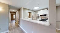This single-floor residence in Asheville, NC is designed with a clean, neutral aesthetic, featuring warm taupe walls, crisp white trim, and wood-look luxury vinyl plank flooring throughout. The open living area is a standout, anchored by a corner fireplace with a white mantle and a sliding glass door with vertical blinds that invites natural light into the space.

The kitchen is well-appointed with white cabinetry, white quartz countertops, a peninsula with bar-height seating, stainless steel appliances including a refrigerator, electric range, built-in microwave, and dishwasher. A skylight overhead enhances brightness, and direct access to the laundry area adds everyday convenience. The dedicated laundry space houses a full-size washer and dryer alongside upper cabinetry for storage.

Bedrooms are comfortably sized, with one featuring large windows overlooking wooded surroundings and a walk-in closet. The bathroom includes a tub-shower combination with tile surround and coordinating flooring. Throughout the unit, textured ceilings, consistent flooring, and a cohesive neutral color scheme create a unified, move-in-ready environment.