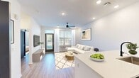 This contemporary 630 square foot apartment offers a thoughtfully designed living space with one bedroom and one bathroom. The open-concept floor plan seamlessly integrates the kitchen, living, and dining areas, creating a sense of spaciousness. The kitchen boasts modern gray cabinetry, stainless steel appliances, and a stylish hexagonal tile backsplash. A white quartz countertop extends to form a breakfast bar with seating for three.

The living room features wood-look flooring, recessed lighting, and a ceiling fan. Large windows and a glass door provide abundant natural light and access to an outdoor space. A sleek entertainment unit with a mounted flat-screen TV serves as a focal point.

The bathroom showcases a double vanity with a expansive mirror and modern fixtures. The bedroom, measuring 170 square feet, includes a built-in closet system for optimal organization. Throughout the apartment, the neutral color palette and clean lines create a fresh, contemporary ambiance. Thoughtful details such as artwork and plants add personality to the space, making it both stylish and functional.