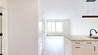 Located at 2132 Stokes Blvd in Cleveland's vibrant University Circle area, this efficiently designed one-bedroom, one-bathroom residence offers a clean, contemporary aesthetic throughout. Light-toned hardwood flooring runs continuously across the entire unit, lending warmth and visual cohesion to every room.

The open-concept kitchen and living area serves as the heart of the home. The kitchen is outfitted with sleek white cabinetry, a white subway tile backsplash, stainless steel appliances including a refrigerator, range, and microwave, and a large peninsula with a quartz countertop and an undermount sink featuring a matte black faucet. A modern linear pendant light anchors the space above.

The bedroom is a bright, well-proportioned retreat with large floor-to-ceiling windows that frame sweeping views of the Cleveland skyline and surrounding neighborhood. Two closets provide ample storage. The bathroom features a frameless glass walk-in shower, contemporary matte black fixtures, and a clean vanity with neutral countertops.

Additional conveniences include an in-unit laundry area. The overall design is defined by crisp white walls, abundant natural light, and a minimalist modern finish palette that creates a fresh, move-in-ready environment.