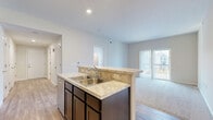Located at 166 Carlton Manor Dr in Sunbury, Ohio, this well-appointed single-floor residence offers three bedrooms, two bathrooms, and a thoughtfully designed open-concept layout. The combined kitchen and living area serves as the heart of the home, anchored by a central island with granite-style countertops, a double stainless steel sink, and a breakfast bar with seating. Dark espresso cabinetry extends floor-to-ceiling, complemented by stainless steel appliances including a range, microwave, and refrigerator. Durable wood-look flooring flows throughout the main living and kitchen areas, while plush carpet adds comfort to the bedrooms. The primary bedroom offers a generous footprint with natural light from dual windows and access to ample closet space featuring wire shelving systems. Eight closets throughout the home provide exceptional storage capacity. The bathrooms are finished with tile flooring and granite-style vanity tops paired with dark cabinetry. A private balcony extends the living space outdoors. Additional highlights include a dedicated laundry area, pantry, utility room, and well-lit hallways connecting each space seamlessly throughout this clean, move-in-ready home.