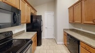 Located at 1200 Greenview Dr in Lynchburg, VA, this single-floor home offers a well-organized layout with distinct living, kitchen, and sleeping areas. The open-concept living and dining space features wood-look laminate flooring and vaulted ceilings with recessed lighting, creating an airy, welcoming atmosphere. A ceiling fan adds functional comfort to the main living area, which also benefits from a sliding glass door that draws in natural light and provides outdoor access.

The kitchen is positioned adjacent to the living area and features warm-toned wood cabinetry, laminate countertops, a tile floor, and a full suite of black appliances including a refrigerator, electric range, and dishwasher. A breakfast bar with seating overhang connects the kitchen to the living space, enhancing the open-plan design.

Bedrooms are carpeted and finished with neutral walls and ceiling fans with light fixtures. At least one bedroom includes direct access to a walk-in closet. Multiple windows in the bedrooms allow for ample natural light and outdoor views.

The bathrooms are functional and clean in design. One features a white vanity with a single-basin sink, tile flooring, a tub-shower combination, and a window with shutters. A second bathroom also includes a tub-shower combination with bronze fixtures. Both bathrooms maintain a consistent neutral color palette throughout.