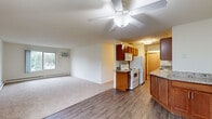 Located at 6904 10th St N in Oakdale, Minnesota, this two-bedroom, one-bathroom residence offers a well-organized single-floor layout. The open living area is a highlight of the home, featuring a combination of wood-style flooring and plush carpeting, ceiling fan, a wall-mounted air conditioning unit, and baseboard heating along the perimeter. Multiple windows invite natural light and provide views of the surrounding neighborhood. The galley-style kitchen is efficiently designed with warm wood cabinetry, granite-look countertops, a full suite of white appliances including a refrigerator, electric range, microwave, and dishwasher, all set atop light wood-style flooring. A connecting hallway links the main living spaces to the bedrooms and bathroom, with a textured ceiling adding architectural interest. Both bedrooms are carpeted and equipped with ceiling fans and baseboard heaters; the primary bedroom includes a sliding-door closet, while the secondary bedroom features a window overlooking the exterior. The bathroom is appointed with a wood-toned vanity, white countertop, and a lighted mirror. This functional and comfortable home provides a practical layout suited for everyday living in a residential Oakdale neighborhood.