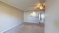 This single-floor residence presents a well-organized layout designed for comfortable everyday living. The spacious living area is finished with plush wall-to-wall carpeting and features a ceiling fan with integrated lighting, crown molding, and a textured ceiling. A half-wall pass-through opening connects the living space directly to the kitchen, promoting an open and airy feel while maintaining a defined separation between the two areas.

The kitchen is equipped with a stainless steel electric range and oven, a ventilation hood, light-toned cabinetry, and a speckled white countertop. A tasteful tile backsplash with a subtle linear pattern adds a decorative touch, while wood-look flooring grounds the space with warmth.

The bedrooms are generously sized, each carpeted and outfitted with ceiling fans and crown molding. Windows fitted with horizontal blinds allow natural light to filter in while providing privacy. The neutral wall tones throughout the unit contribute to a calm, cohesive atmosphere.

The bathroom includes a vanity with a speckled white countertop and under-sink cabinetry, a framed mirror, and a tiled bathtub and shower combination with wood-look flooring. The layout is efficient and functional, making thoughtful use of the available space throughout each room.