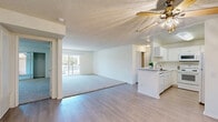 Located in the North Hollywood neighborhood of Los Angeles, this 2-bedroom, 2-bathroom residence at 4335 Vineland Ave offers a well-organized single-floor layout. The open-concept living and dining area is anchored by light wood-style flooring, a ceiling fan, and a sliding glass door that leads to a private balcony with outdoor views — bringing natural light deep into the space. The kitchen flows seamlessly into the living area and features white cabinetry, a peninsula with a sink, white appliances including a range, microwave, and refrigerator, and light countertops, creating a clean and functional workspace. Both bedrooms are carpeted and generously proportioned, with the primary bedroom offering a notably spacious footprint. Each bedroom is equipped with mirrored sliding closet doors and windows that provide natural light and views of the surrounding greenery. The two bathrooms each include a tub-shower combination with tile surround and light wood-style flooring, maintaining a consistent, clean aesthetic throughout. Textured ceilings are present across the entire residence. The overall ambiance is bright, neutral, and move-in ready, offering a practical and comfortable living environment in a well-connected Los Angeles location.