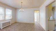 Located at 1926 Market Ave N in Canton, Ohio, this single-floor home offers a thoughtfully arranged layout with a blend of classic architectural details and practical living spaces. The living room serves as a central gathering area, highlighted by a traditional wood-surround fireplace with a refined mantel, neutral carpeting, and a tiled ceiling that adds a vintage character to the room. A wall sconce and large front-facing windows bring in natural light, creating a warm and welcoming atmosphere. Adjacent to the living area, a generously sized room features an elegant chandelier, crown molding, and soft carpeting underfoot, making it well-suited as a dining room or flex space. The bedrooms offer comfortable proportions with plush carpeting and multiple windows fitted with blinds, allowing ample daylight to fill the rooms. The kitchen is efficiently designed with white cabinetry, including glass-front upper cabinets, dark hardwood-style flooring, and a back door with a glass panel that introduces additional natural light. The layout connects seamlessly through interior doorways, creating a cohesive and accessible flow throughout the home. Classic trim work, neutral wall tones, and a mix of ceiling styles contribute to the home's enduring character.
