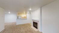 Located in Portland, Oregon, this single-floor residence offers a clean, neutral aesthetic throughout, with white walls and a consistent design palette that creates a bright, cohesive atmosphere. The open living area serves as the heart of the home, featuring a tile-surround fireplace as a central focal point, plush wall-to-wall carpeting, and a half-wall breakfast bar that connects seamlessly to the kitchen. This layout promotes an easy flow between the living and dining spaces.

The galley-style kitchen is efficiently organized, with white cabinetry lining both sides, a full suite of white appliances including a refrigerator, range, microwave, and dishwasher, and wood-look flooring that adds warmth underfoot. Track lighting illuminates the workspace effectively.

The bedrooms are carpeted and offer a quiet, comfortable retreat, with at least one room featuring a closet with sliding panel doors and overhead shelving for storage. The bathrooms include wood-look tile flooring, vanities with ample counter space, and a soaking tub with a shower. A dedicated in-unit laundry area accommodates a full-size washer and dryer, accompanied by overhead shelving for added convenience.