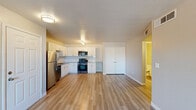 This single-story, 3-bedroom, 1-bathroom residence offers a practical and modern layout designed for comfortable living. The open-concept kitchen and living area forms the heart of the home, featuring wood-look plank flooring, white cabinetry with tile backsplash, and a full suite of stainless steel appliances including a refrigerator, gas range, and built-in microwave. A closet near the kitchen provides convenient storage. The living room is bright and airy, enhanced by a ceiling fan and a sliding glass door that opens to a private patio with views of palm trees and the surrounding landscape, allowing for generous natural light.

The three bedrooms continue the wood-look flooring and neutral color palette seen throughout the unit. Each room is equipped with a ceiling fan and window with blinds for light control. The primary bedroom offers additional closet space with sliding doors and a walk-in closet area. One bedroom features direct sliding glass door access to the outdoor patio, while another secondary bedroom is compact and well-suited as a guest room or home office.

The shared bathroom is clean and functional, featuring a combined tub and shower with a curved rod and neutral finishes. A hallway connects all rooms, completing this efficient and cohesive floor plan.