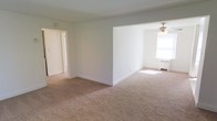 Located at 1 Martha Avenue in Wrightstown, New Jersey, this single-floor residence offers a clean, functional layout with a straightforward and practical design. The interior is finished with neutral white walls throughout, creating a bright and open atmosphere that allows natural light to play a central role in the overall ambiance.

The main living area is carpeted in a warm beige tone, providing a comfortable and cohesive feel underfoot. The space is open and connected, with a partial wall division that separates areas while maintaining a sense of continuity and flow between them. A ceiling fan is installed in one section of the living space, contributing to both comfort and air circulation.

Natural light enters through a window fitted with a radiator beneath it, suggesting a traditional heating system is in place. The doorways are clean and simply framed, leading to additional rooms including what appears to be a hallway or utility space visible through an open door. White baseboards provide a crisp contrast to the carpeted floors throughout.

Overall, the home presents a modest, well-maintained interior with a calm, neutral palette. Its single-floor layout makes for easy navigation, and the open living areas offer flexibility for a variety of furniture arrangements and uses.